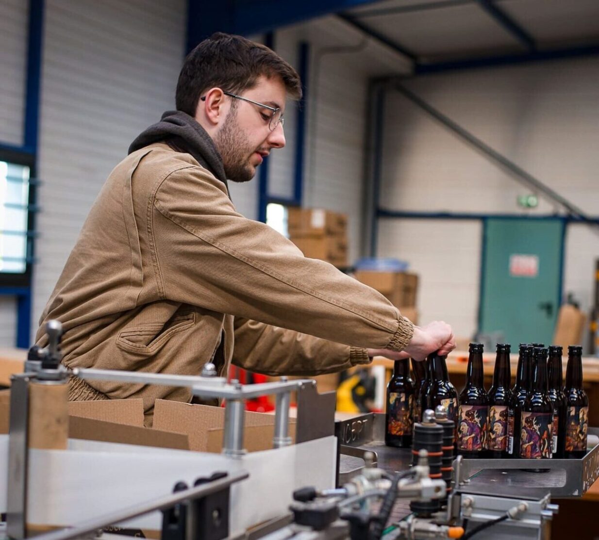 Membre de la brasserie Les Alchimistes Ivres à Broons, en train d’embouteiller des bières artisanales sur la ligne de production.